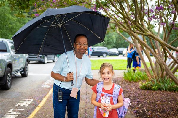 teacher with umbrella walking with student